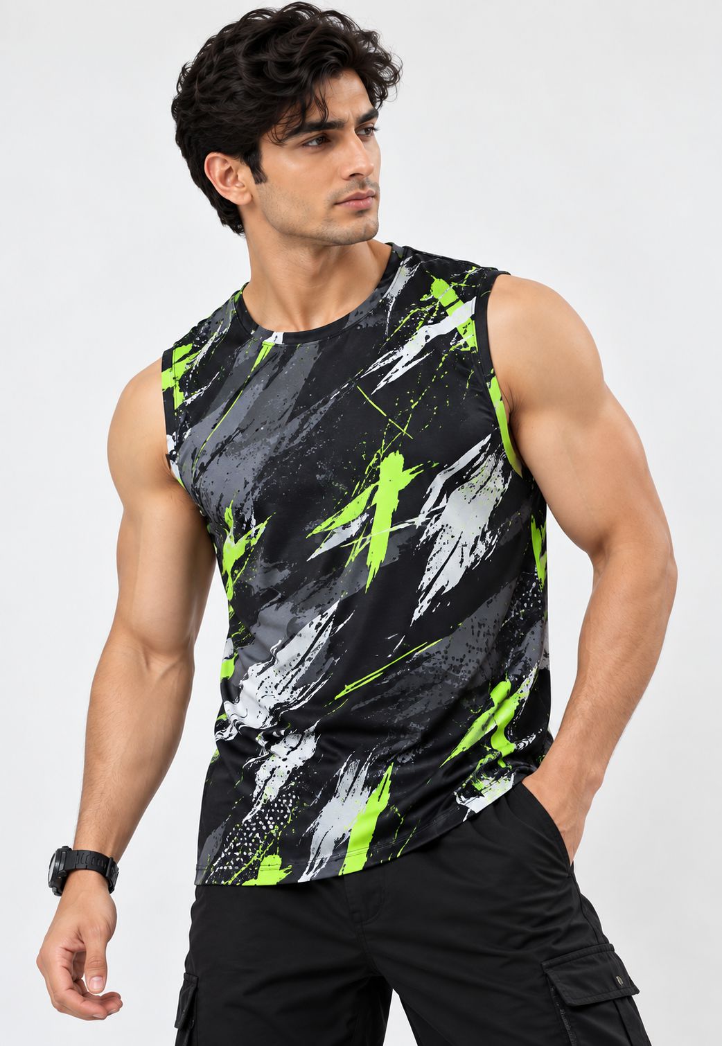 A muscular man wearing a sleeveless athletic tank top with a black, gray, and neon green abstract brushstroke pattern, paired with black cargo pants, against a light gray studio background.