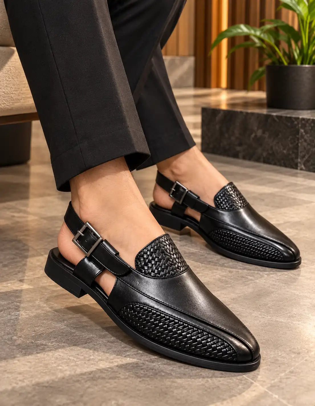 Black Peshawari sandals worn on both feet, showing woven panels and buckle straps