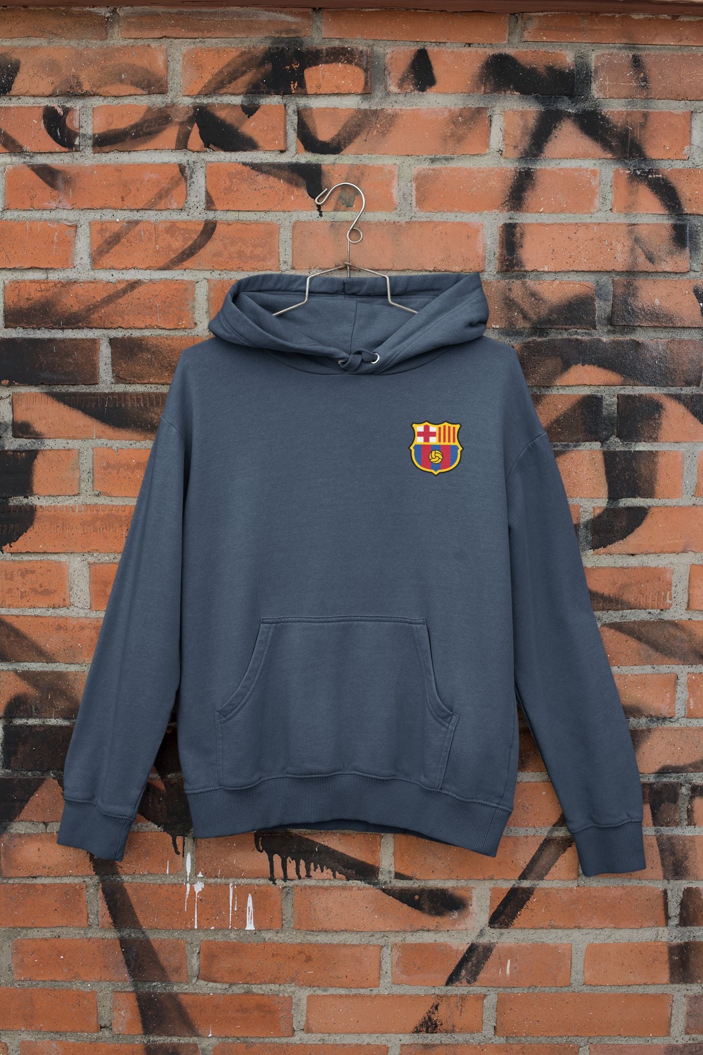 Blue hoodie with a logo on a brick wall with graffiti