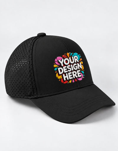 A black trucker-style sports cap with a curved brim and perforated mesh back panels, featuring a colorful graphic on the front that reads 'YOUR DESIGN HERE' in white text over a pink, blue, yellow, and orange paint splatter design. The cap is photographed on a clean white background.