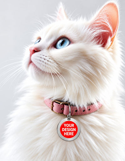 A fluffy white cat with blue eyes wearing a pink collar with a round customizable silver tag that reads 'YOUR DESIGN HERE' on a light gray background.