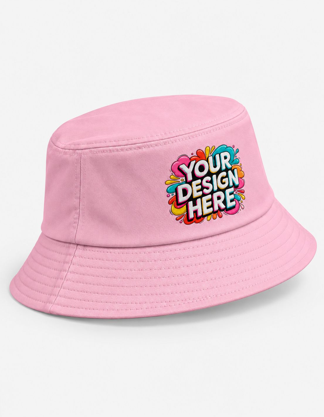 A light pink bucket hat with a colorful 'YOUR DESIGN HERE' mockup graphic on the front, set against a plain white background.