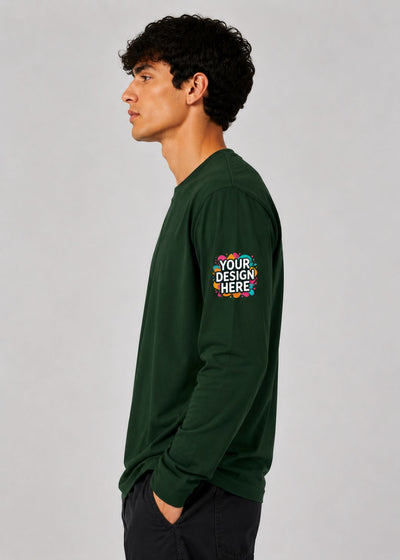 A man in profile wearing a dark green long-sleeve t-shirt with a colorful mockup graphic on the left sleeve that reads 'YOUR DESIGN HERE', set against a plain light gray studio background.