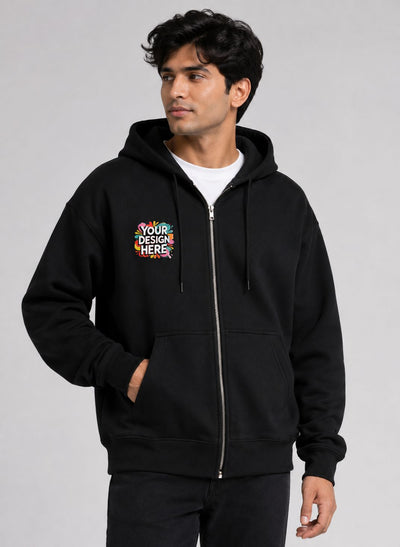 A man wearing a black zip-up hoodie with a colorful 'YOUR DESIGN HERE' mockup graphic on the left chest, photographed against a neutral gray studio background.