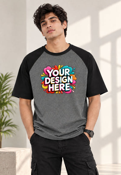 A man wearing a custom raglan t-shirt with a colorful 'YOUR DESIGN HERE' mockup graphic on the chest, set against a bright, modern indoor background.
