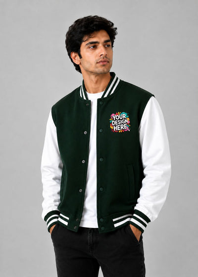 A man wearing a dark green and white varsity jacket with a colorful 'YOUR DESIGN HERE' mockup patch on the left chest, posed against a solid gray studio background.