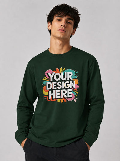 A man wearing a dark green long-sleeve crewneck sweatshirt with a colorful 'YOUR DESIGN HERE' mockup graphic on the chest, set against a plain light gray studio background.
