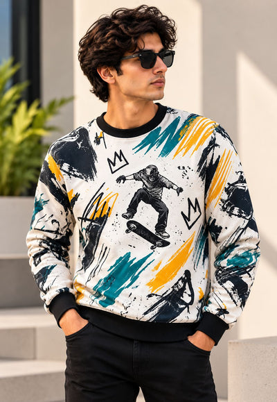 A man wearing a white crewneck sweatshirt with a colorful abstract graphic print, black sunglasses, and black pants, standing outdoors against a modern light-colored wall.