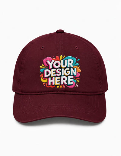 A maroon baseball cap with a colorful 'YOUR DESIGN HERE' graphic printed on the front, set against a plain white background.