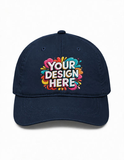 A navy blue baseball cap with a colorful custom graphic on the front that reads 'YOUR DESIGN HERE' in white letters surrounded by a pink, orange, yellow, and blue paint splatter design, shown on a plain white background.