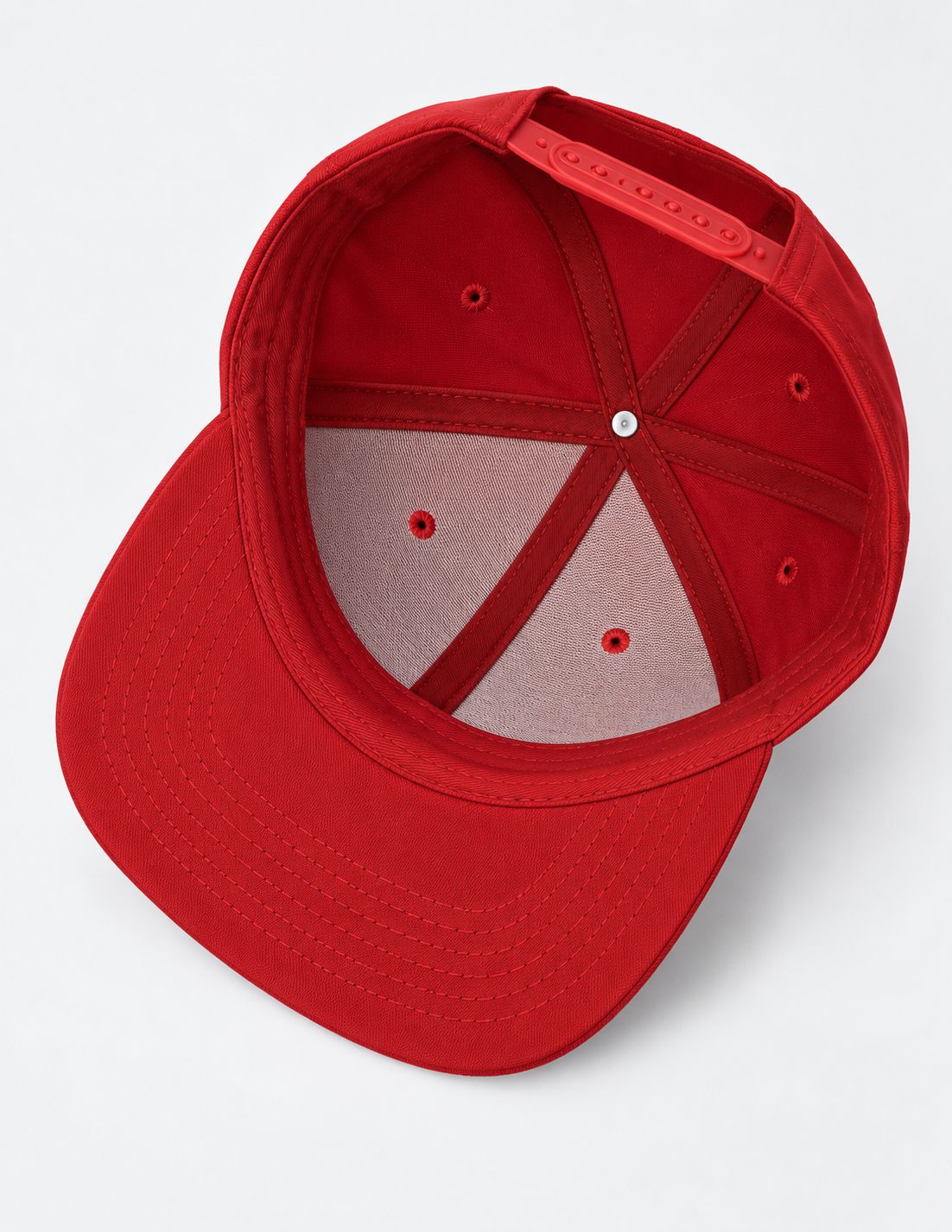 A red structured snapback cap shown from an overhead angle, displaying the interior structure, ventilation eyelets, and adjustable back strap on a light gray background.