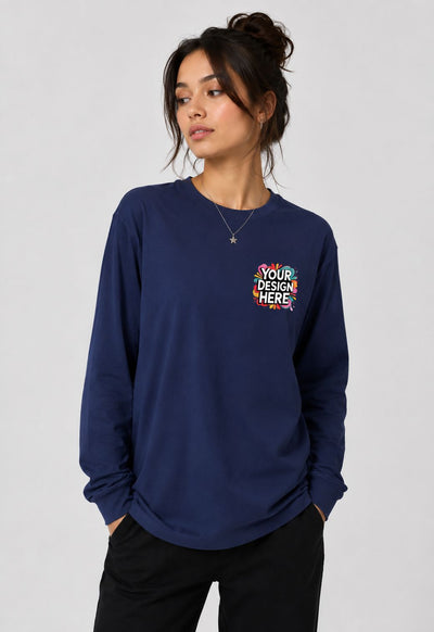 A woman wearing a navy blue long-sleeve crewneck sweatshirt with a colorful 'YOUR DESIGN HERE' mockup graphic on the left chest, paired with black pants, against a light gray studio background.