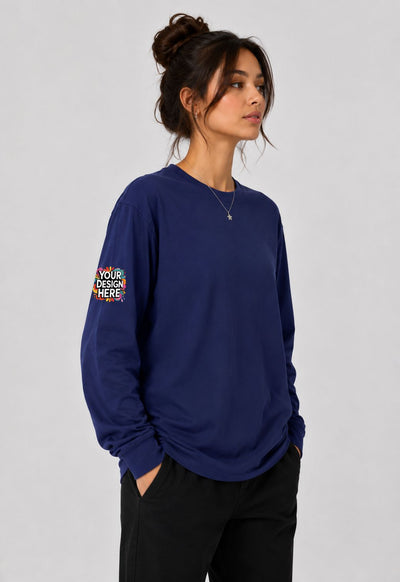 A woman wearing a navy blue long-sleeve crewneck sweatshirt with a colorful graphic print on the left sleeve, paired with black pants, against a light gray studio background.