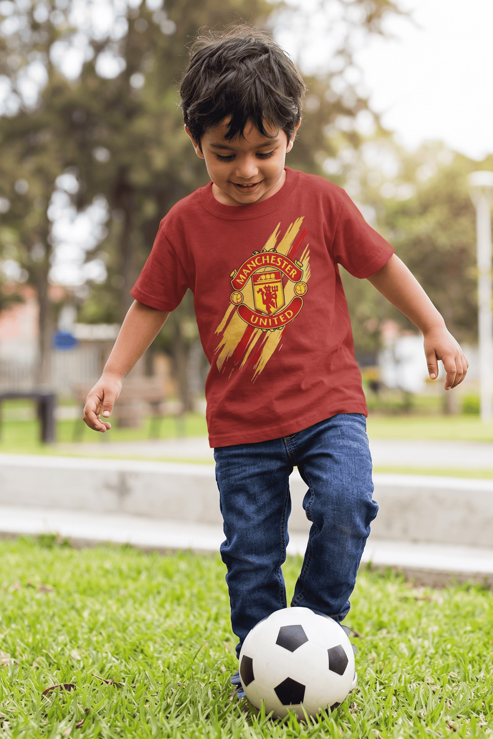Young boy wearing Manchester United inspired football graphic t-shirt while playing soccer outdoors