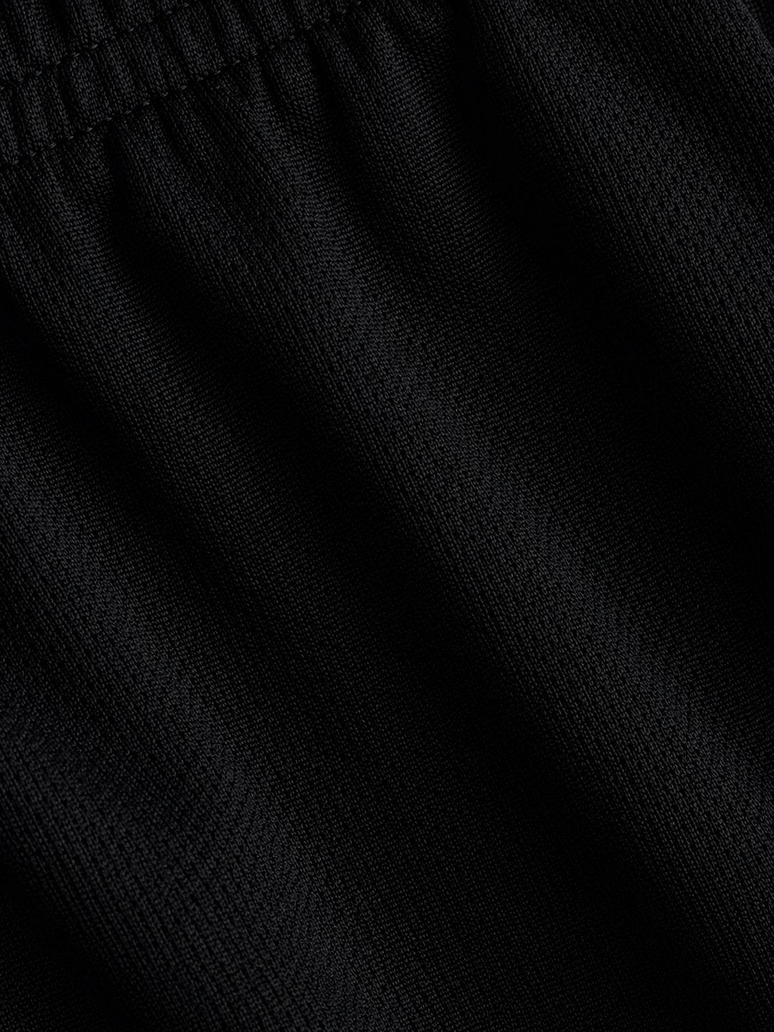 Close-up of black textured knit fabric with a gathered elastic waistband.