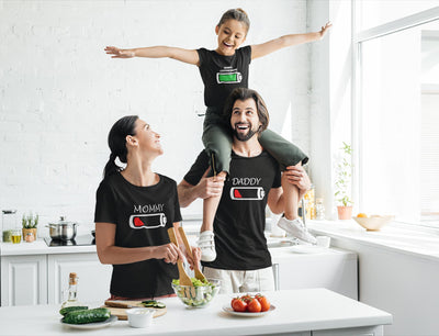 Family of three wearing matching black t-shirts with battery designs.