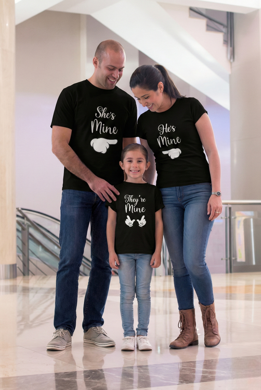 Family of three wearing matching black t-shirts with text in a mall.