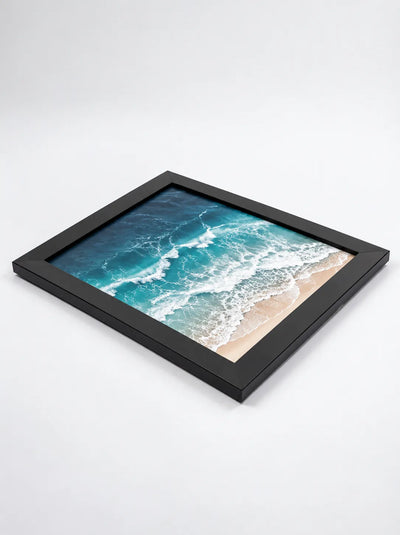 Framed ocean beach poster lying flat with black border