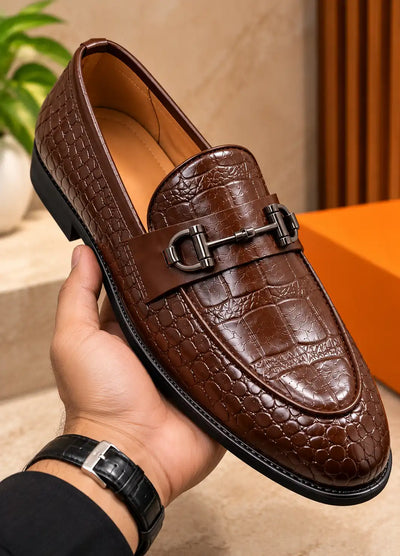 Brown croc-texture loafer with a metal buckle, shown close up