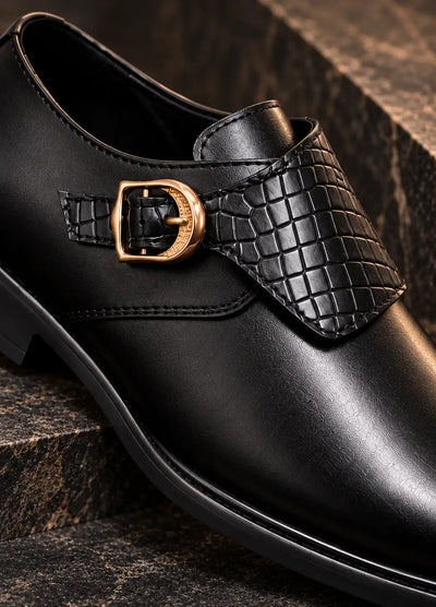 Black monk strap shoe close-up showing woven faux leather panel and gold-tone buckle