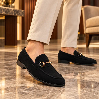 Black suede-look horsebit moccasins worn with light trousers