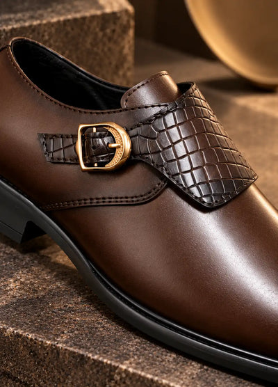 Brown monk strap shoe close-up showing woven faux leather panel and gold-tone buckle
