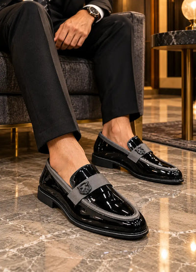 Black patent loafers with gray emblem straps worn with cropped black trousers