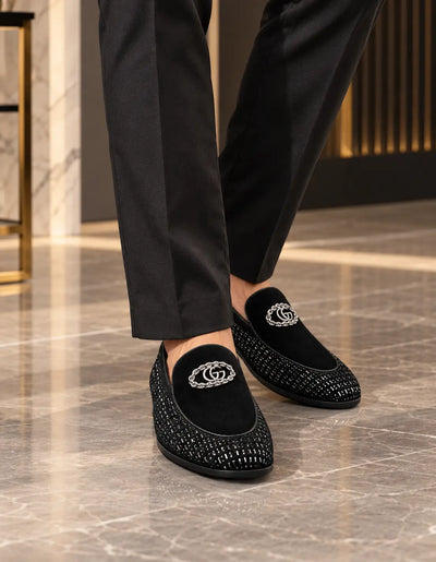 Black embellished moccasin loafers worn with dark trousers