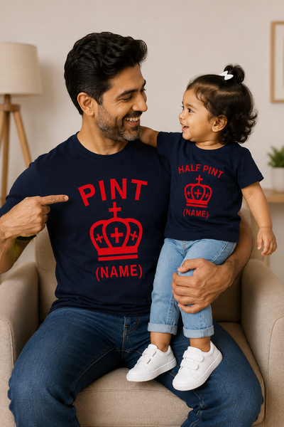 Man and child wearing matching navy blue shirts with red text and graphics, sitting on a couch.