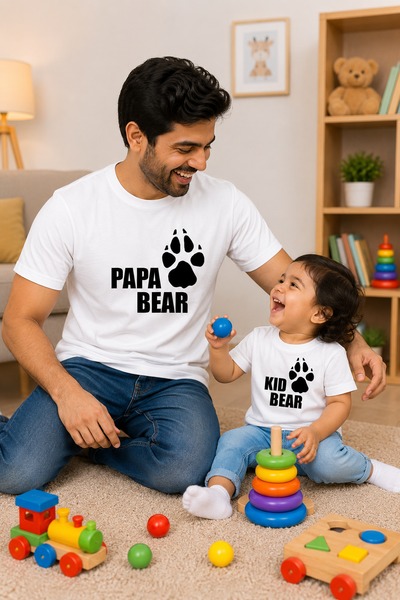 Man and child sitting on the floor with 'Papa Bear' and 'Kid Bear' shirts, surrounded by toys.