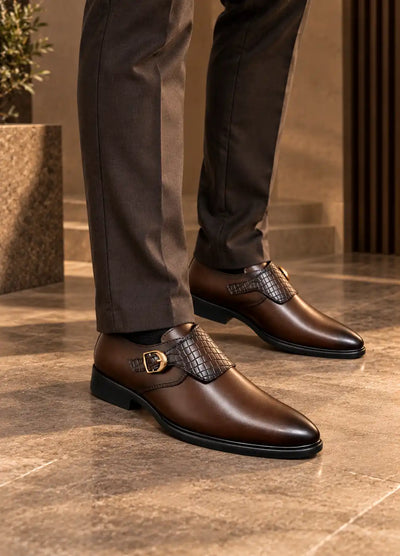 Brown faux leather monk strap shoes with woven panels and gold-tone buckles, worn with trousers