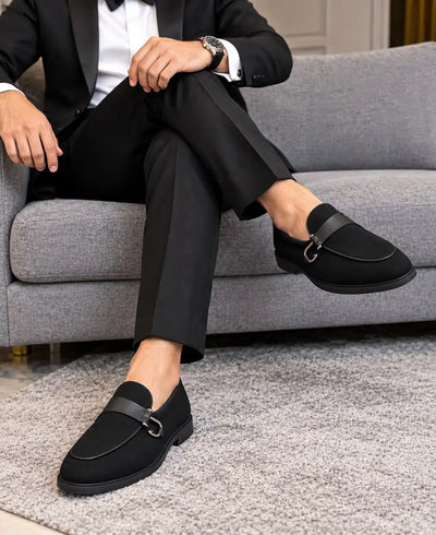 Black suede-finish loafers with metal bit straps, modeled with a suit
