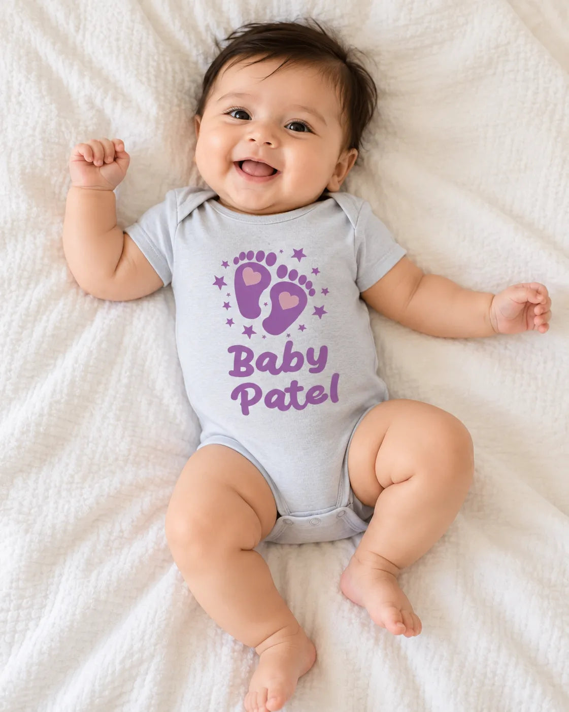 Light grey baby romper bodysuit with purple 'Baby Patel' print and snap legs