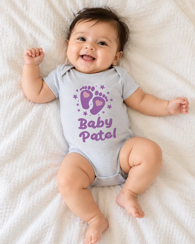 Light grey baby romper bodysuit with purple 'Baby Patel' print and snap legs