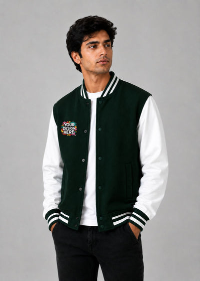 A man wearing a dark green and white varsity jacket with a colorful 'YOUR DESIGN HERE' mockup patch on the left chest, posed against a solid gray studio background.