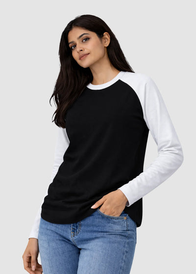 Woman wearing a black and white long-sleeve shirt with blue jeans on a light gray background